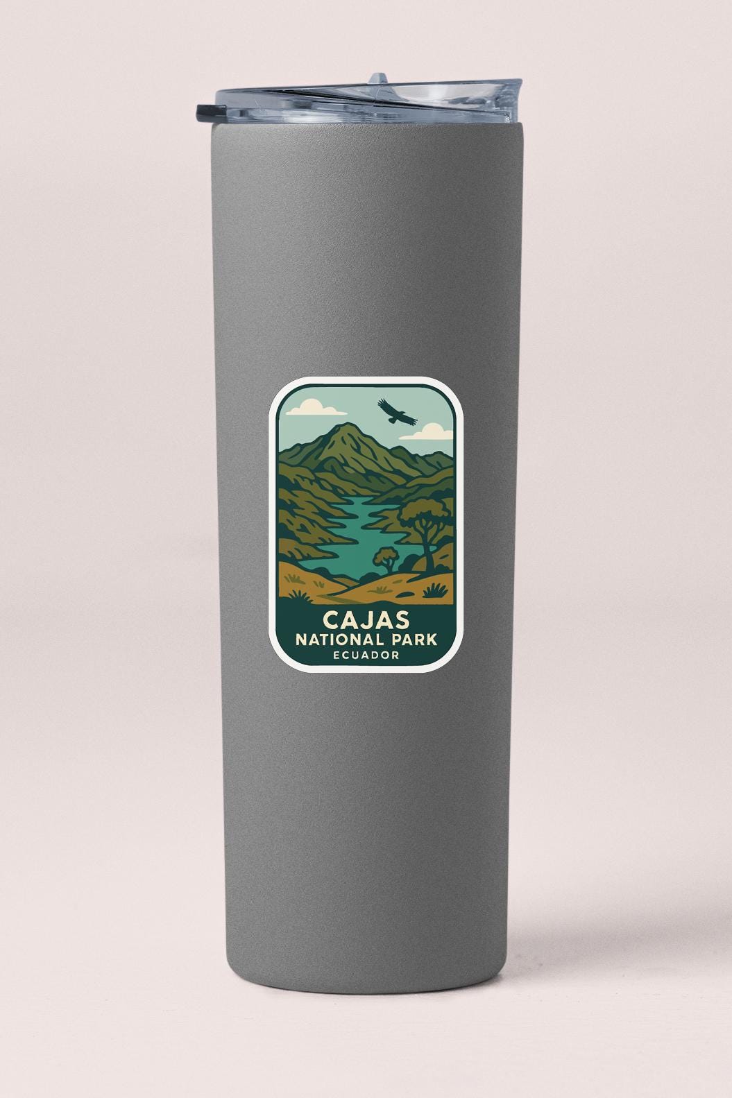 A gray cylindrical container with a label that features a landscape with mountains, a river, and a bird in flight.