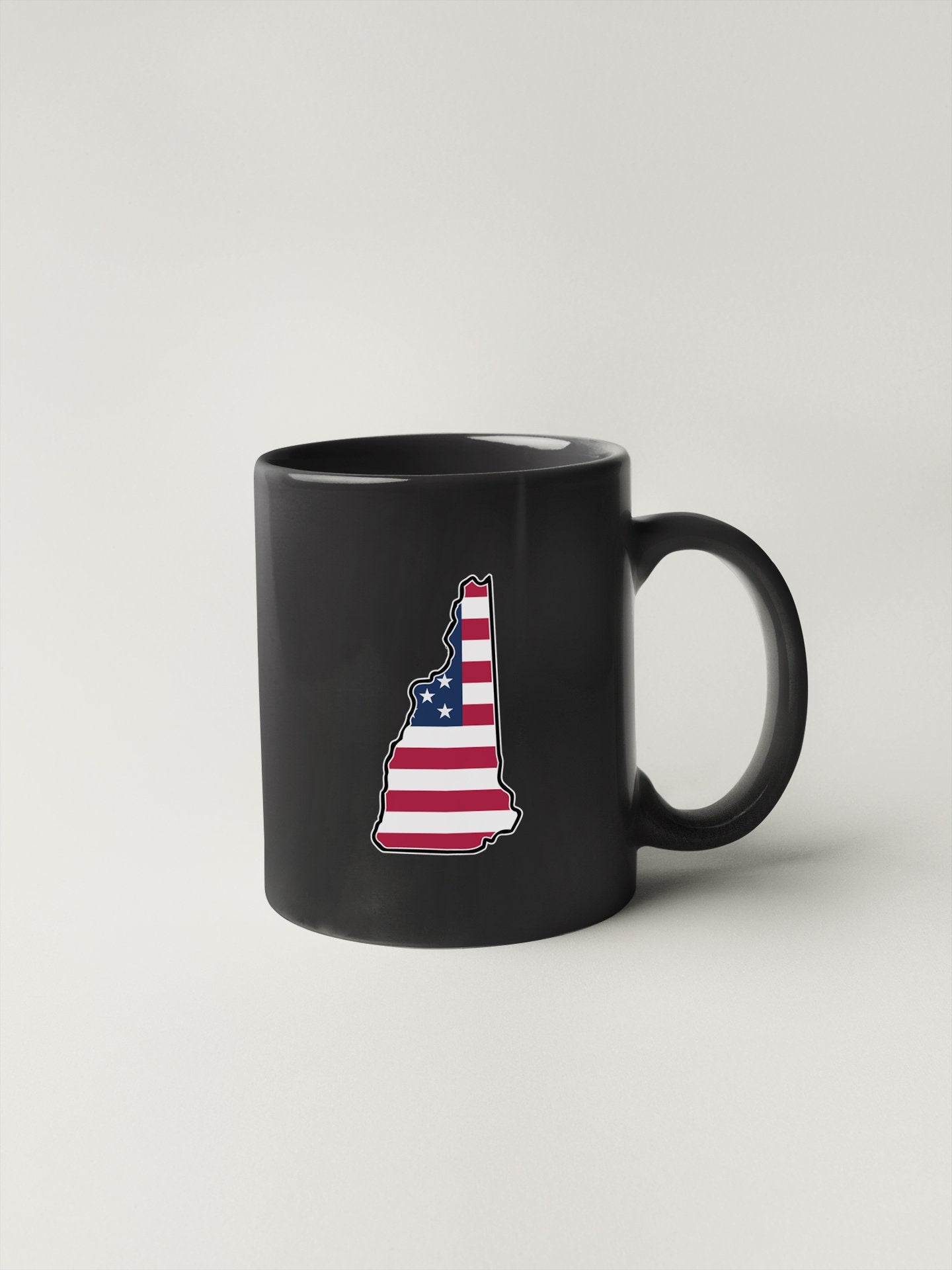 a black coffee mug with the state of new hampshire painted on it
