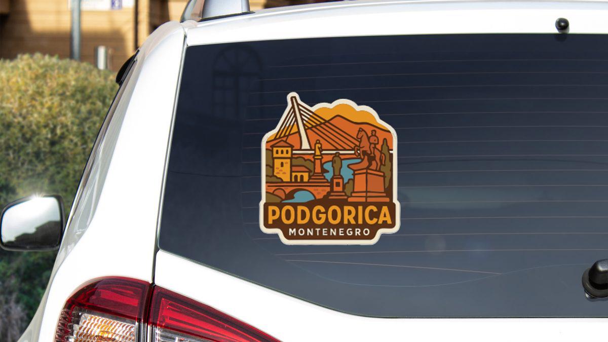 a sticker on the rear window of a car, depicting a scenic view of a city with mountains in the background.