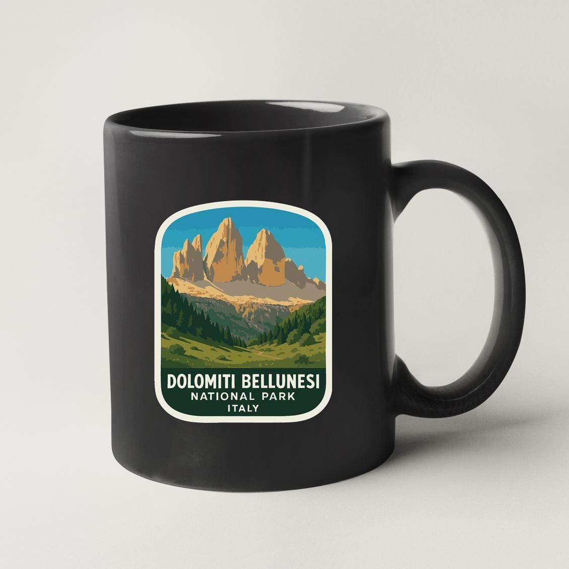 A black coffee mug with a label that says "DOLOMITI BELLUNESI NATIONAL PARK ITALY".