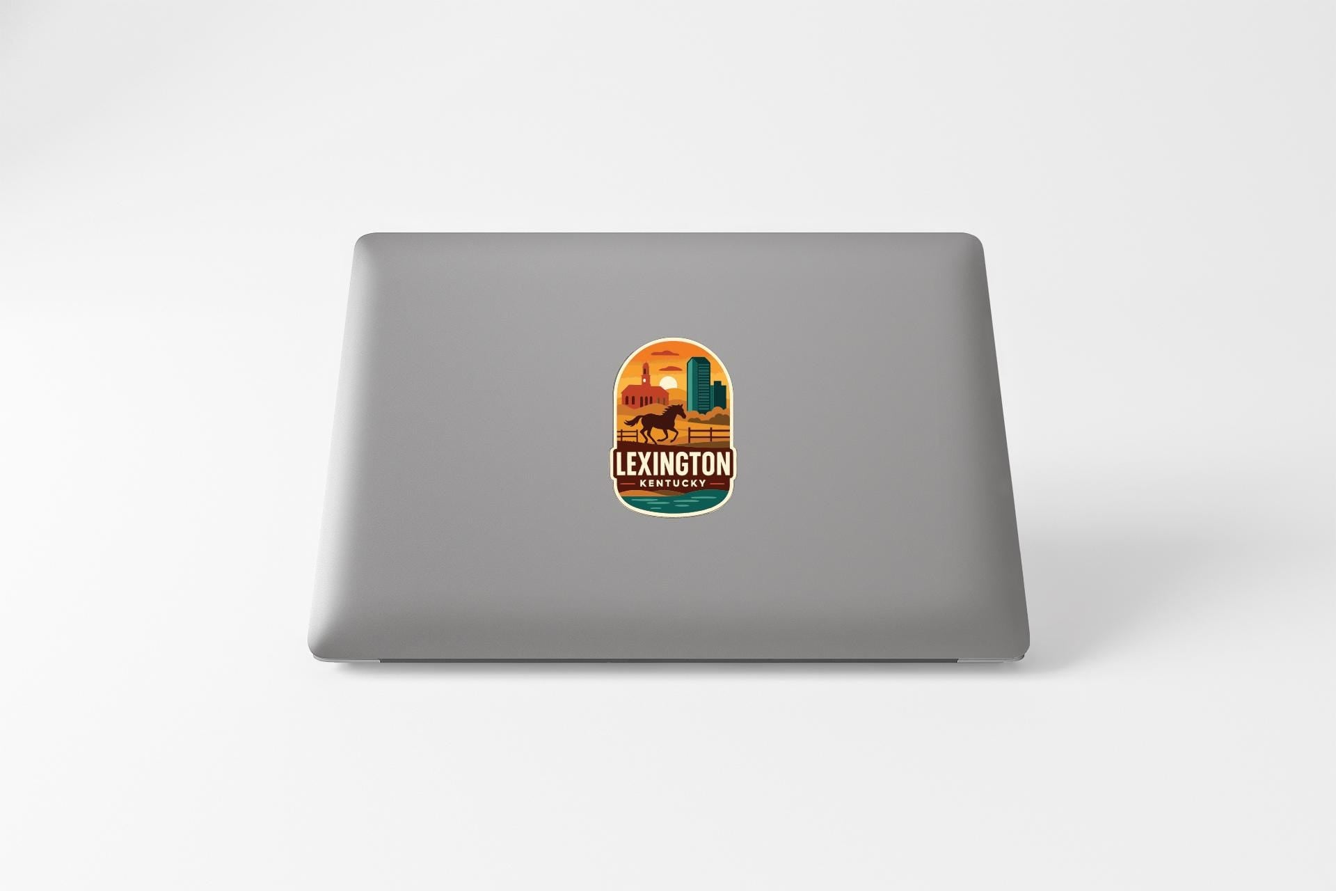 A sticker with an illustration of a desert landscape and the text "LEXINGTON, KENTUCKY" printed on a laptop.