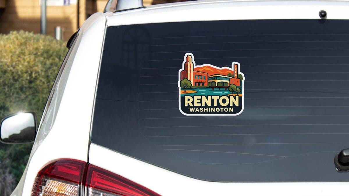 A sticker on the rear window of a white car, depicting a cityscape with a tall building and the text "Renton, Washington".