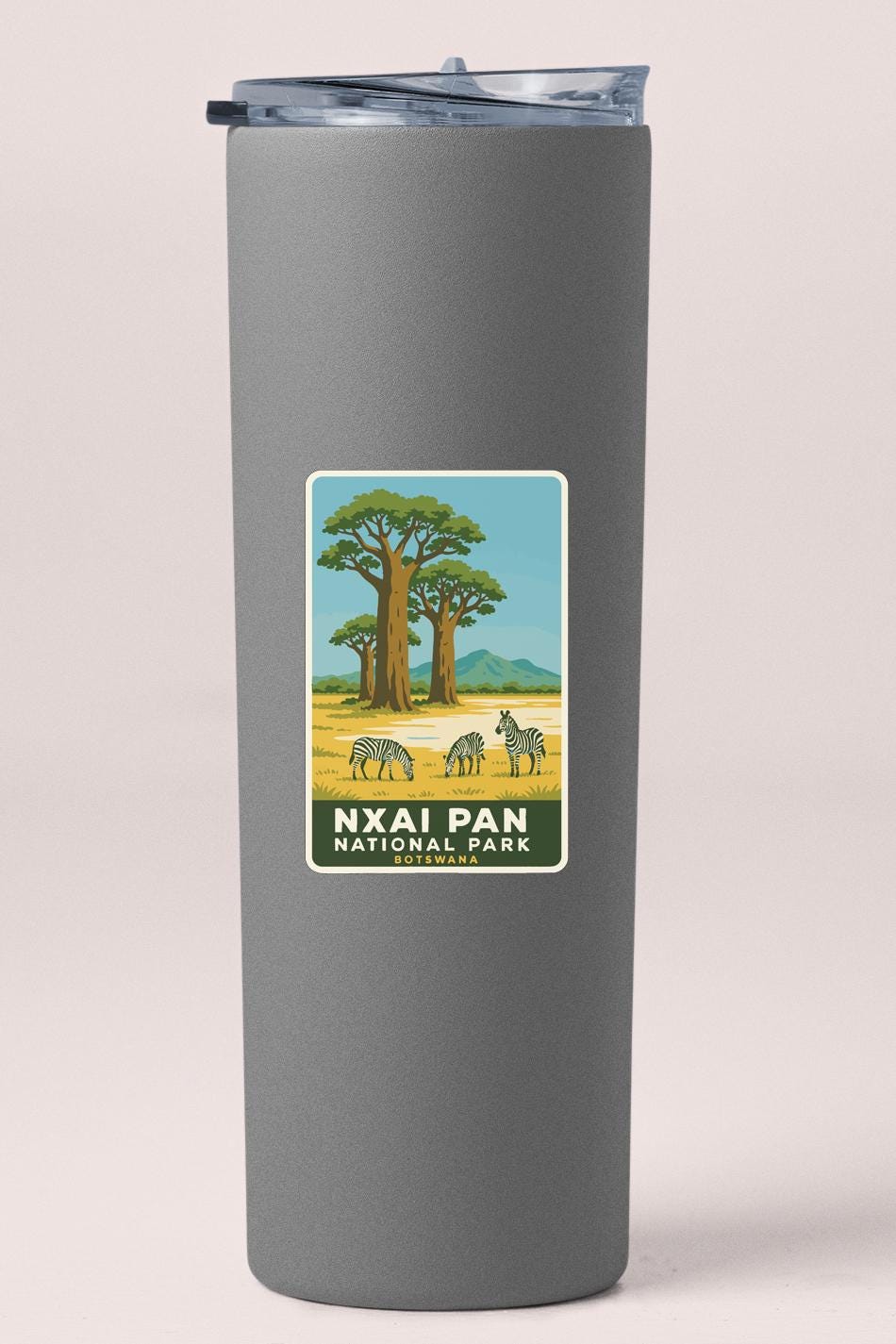 A gray tumbler with a label that features an illustration of zebras in a savanna landscape, along with the text "NXAI PAN NATIONAL PARK".