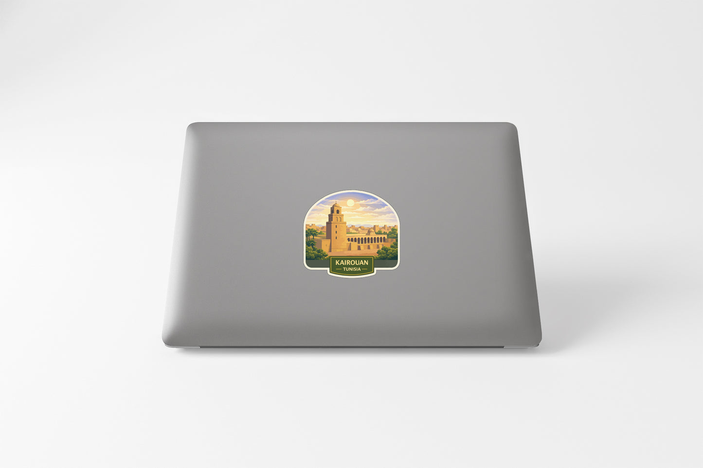a sticker of a building with a sunset in the background on the back of a laptop.