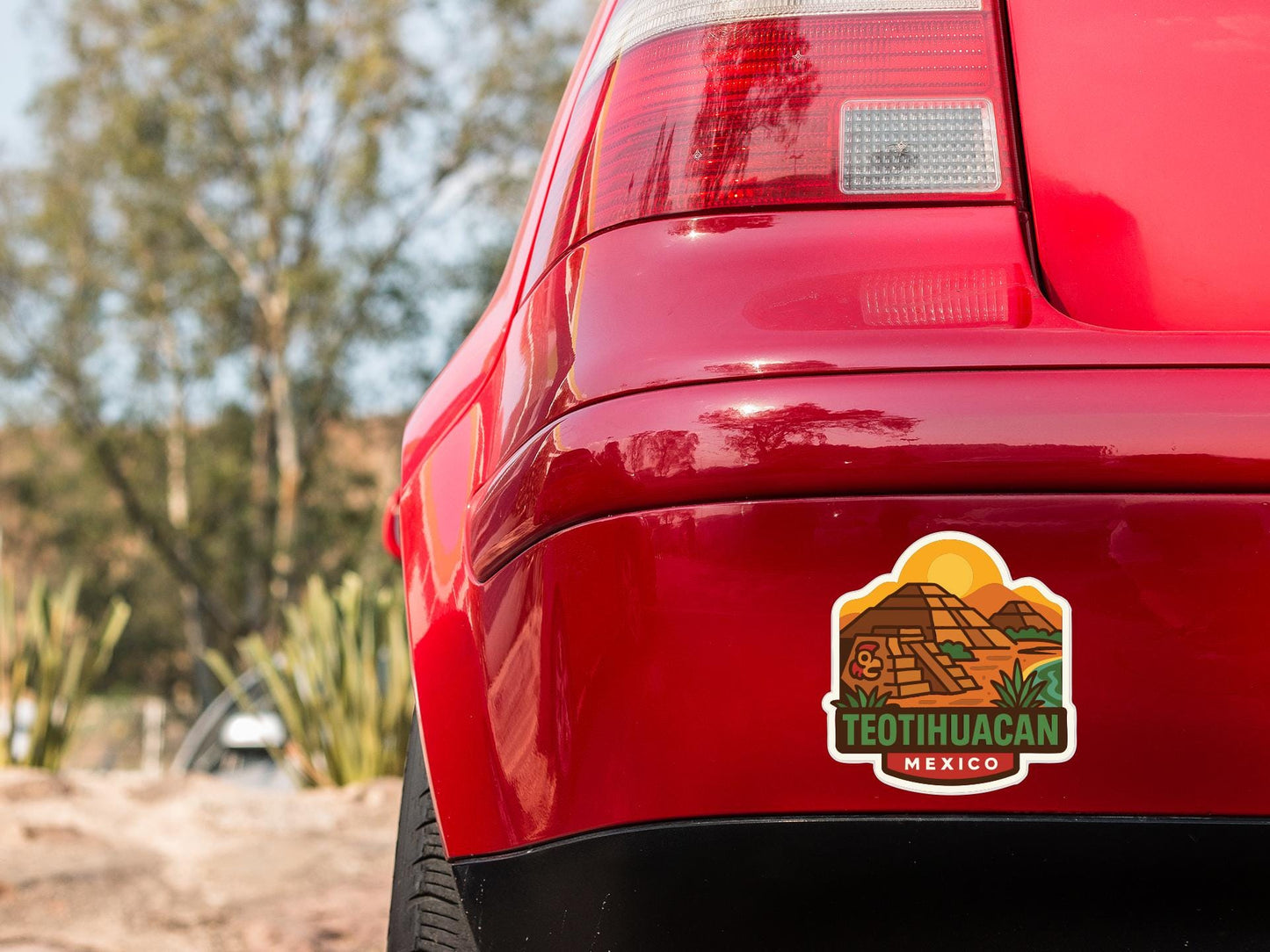 the rear end of a red car with a sticker on the trunk that says "TEETHHUACAN MEXICO".