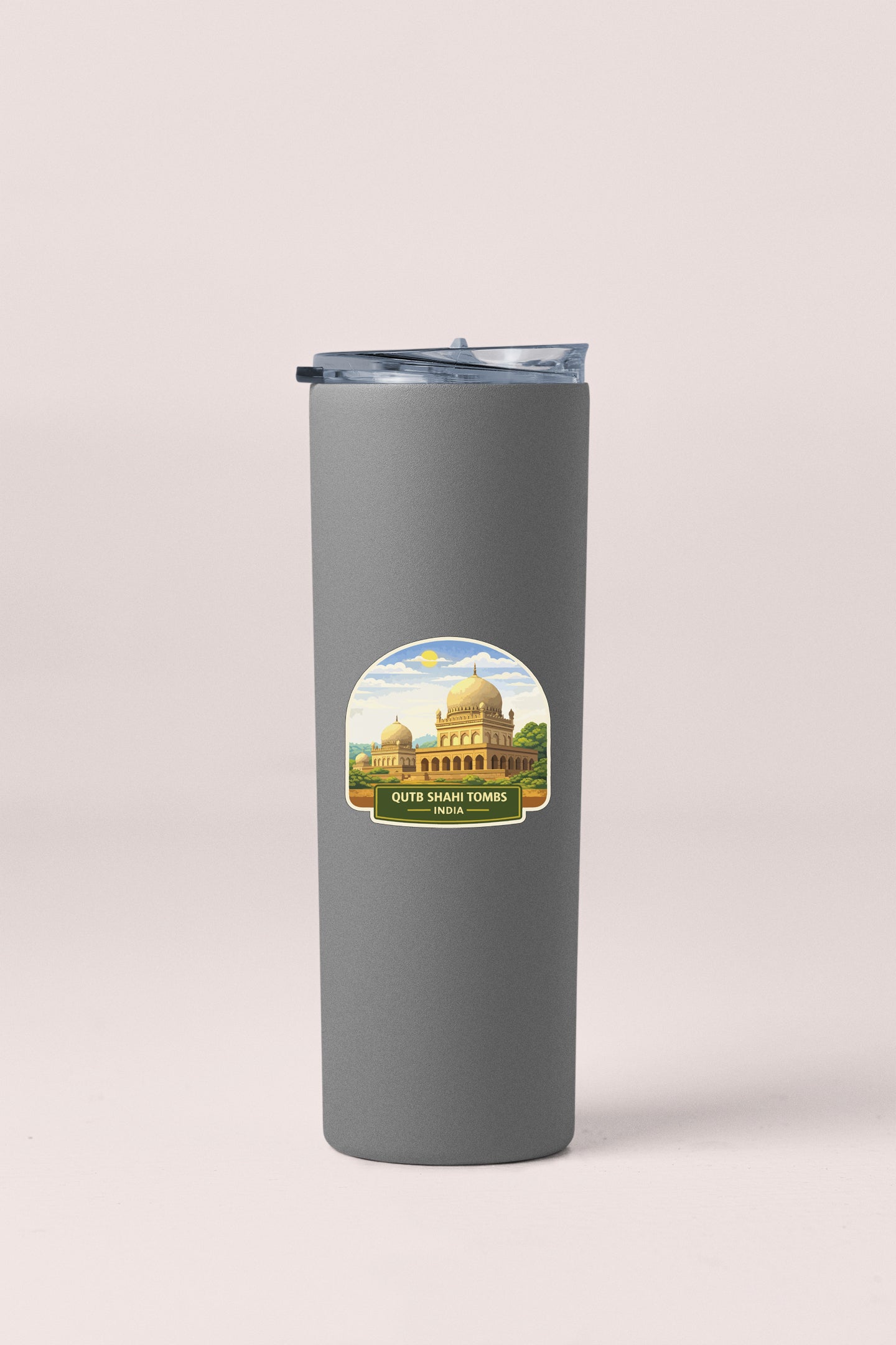 A gray insulated tumbler with a sticker depicting a building and the text "Out of India" and "Tibetan Monastery".