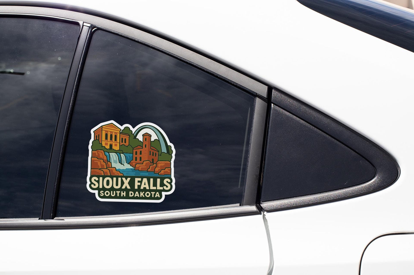 A sticker on the side of a car window, depicting a scenic landscape with a waterfall and buildings, advertising the state of South Dakota.