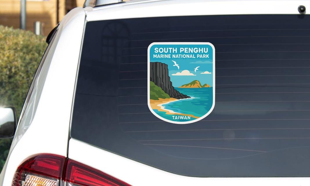 A sticker on the rear window of a car, depicting a scenic landscape with mountains, a beach, and a body of water.