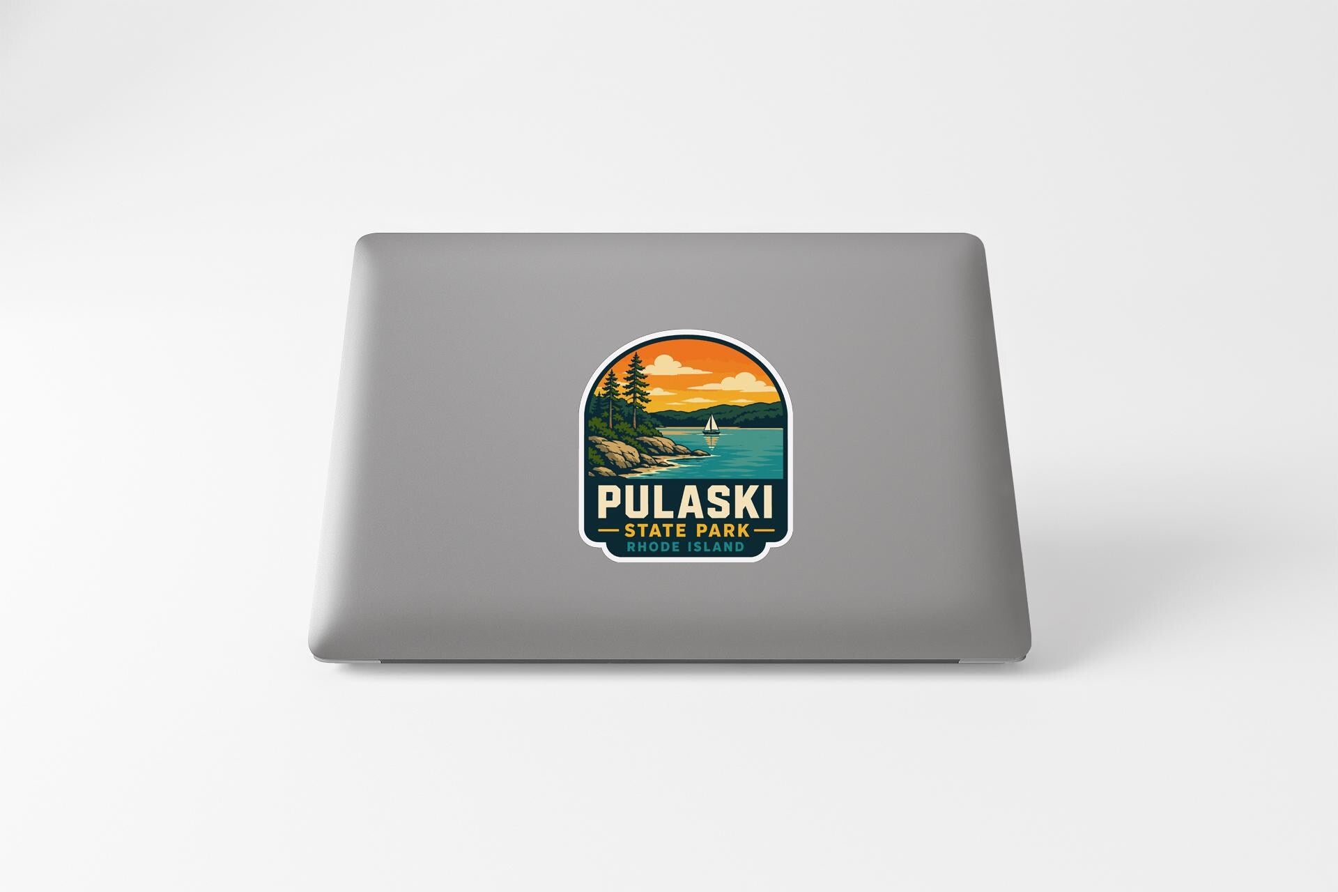 A sticker on the back of a laptop, depicting a scenic landscape with a lake, mountains, and a sunset.