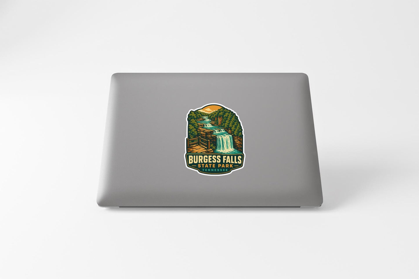 A sticker featuring a scenic illustration of a waterfall and forest on the back of a laptop.