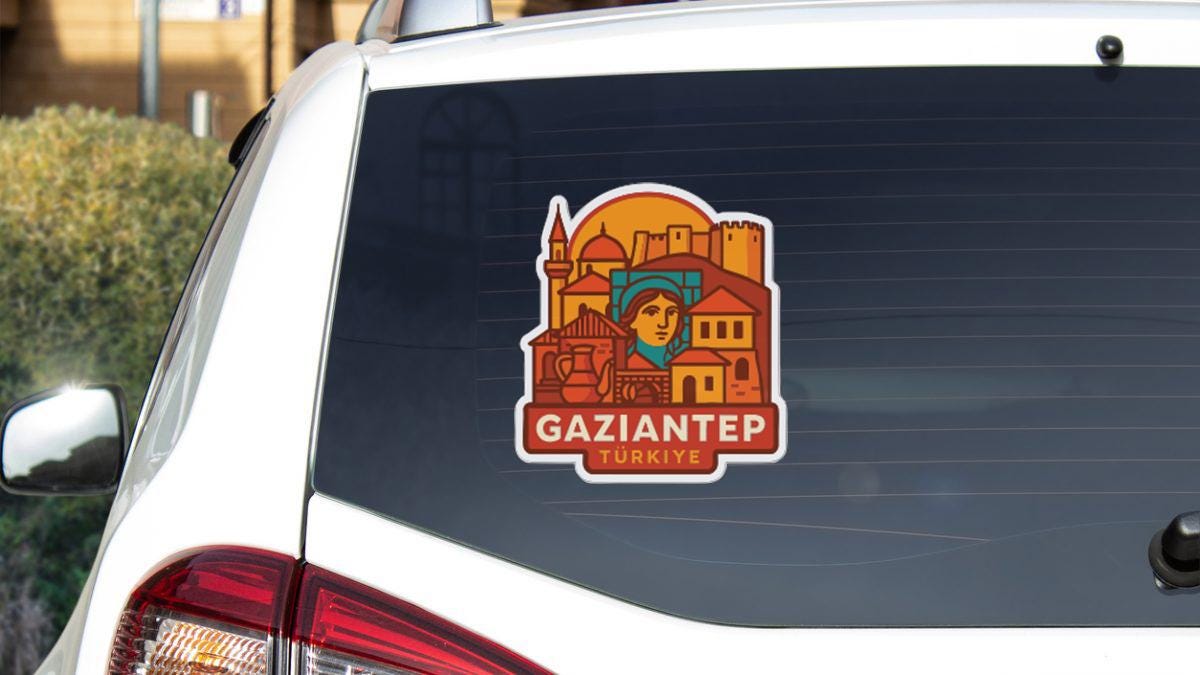 A sticker on the rear window of a white car, depicting a cityscape with a prominent figure in the center.