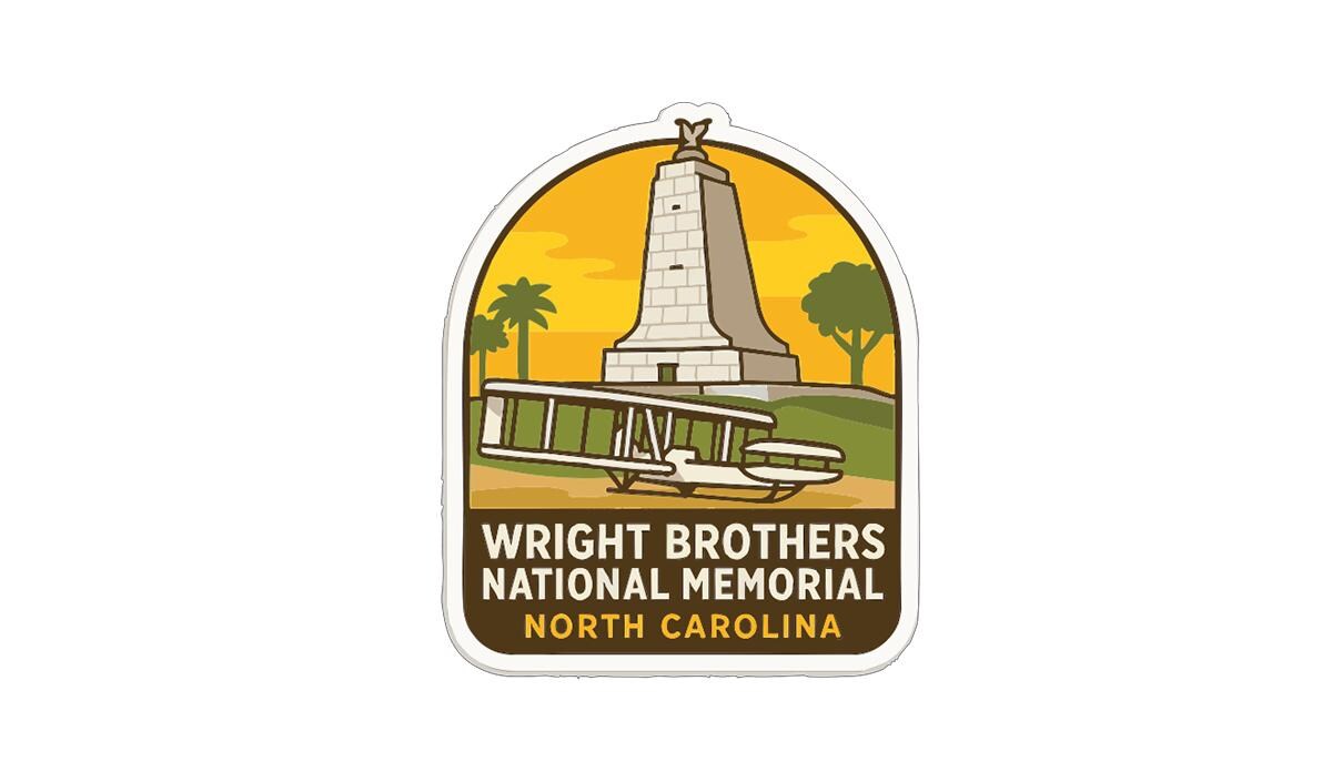 a sticker or emblem with a tall tower and a biplane, representing the Wright Brothers National Memorial in North Carolina.