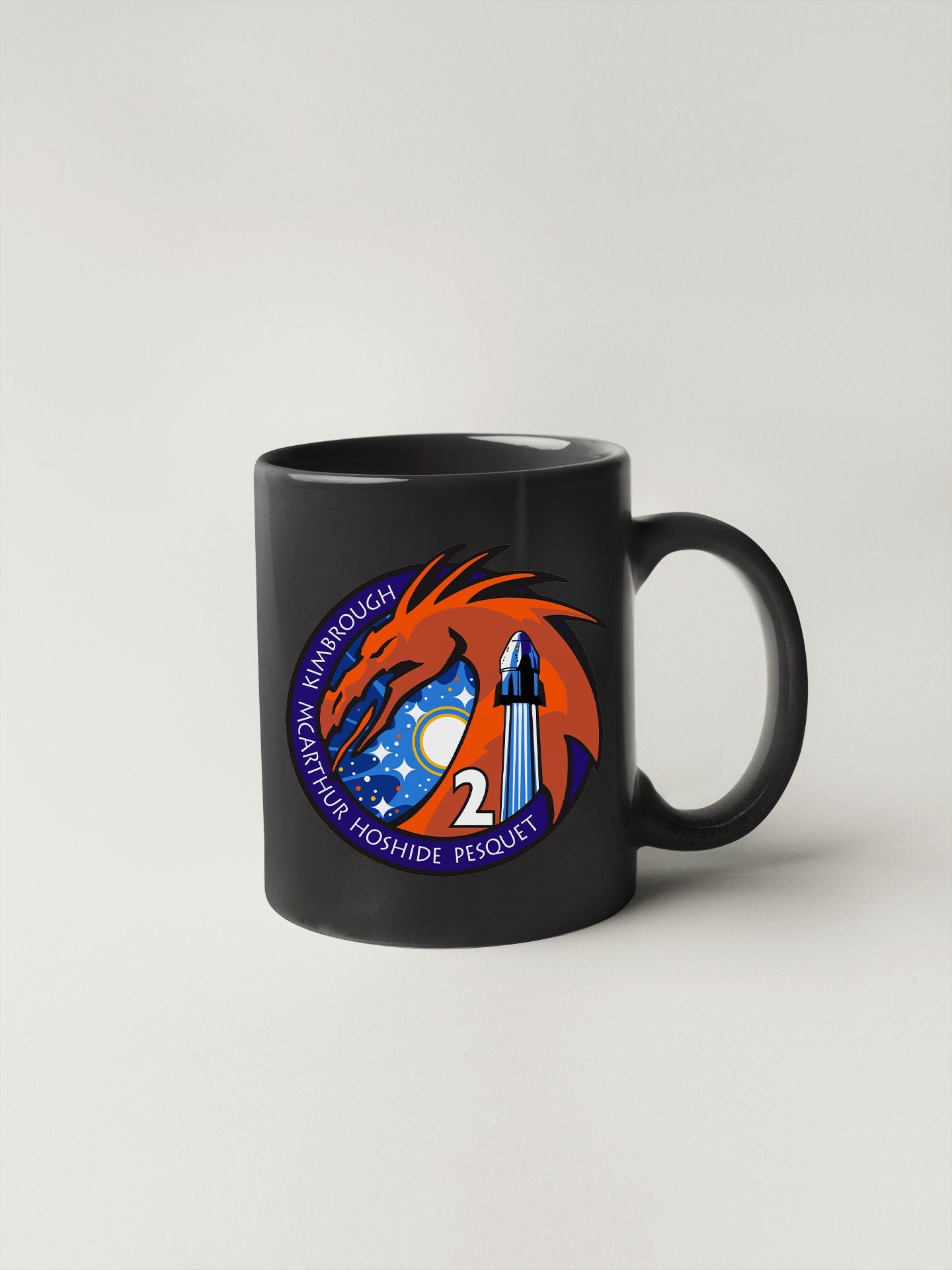 a black coffee mug with a picture of a rocket on it