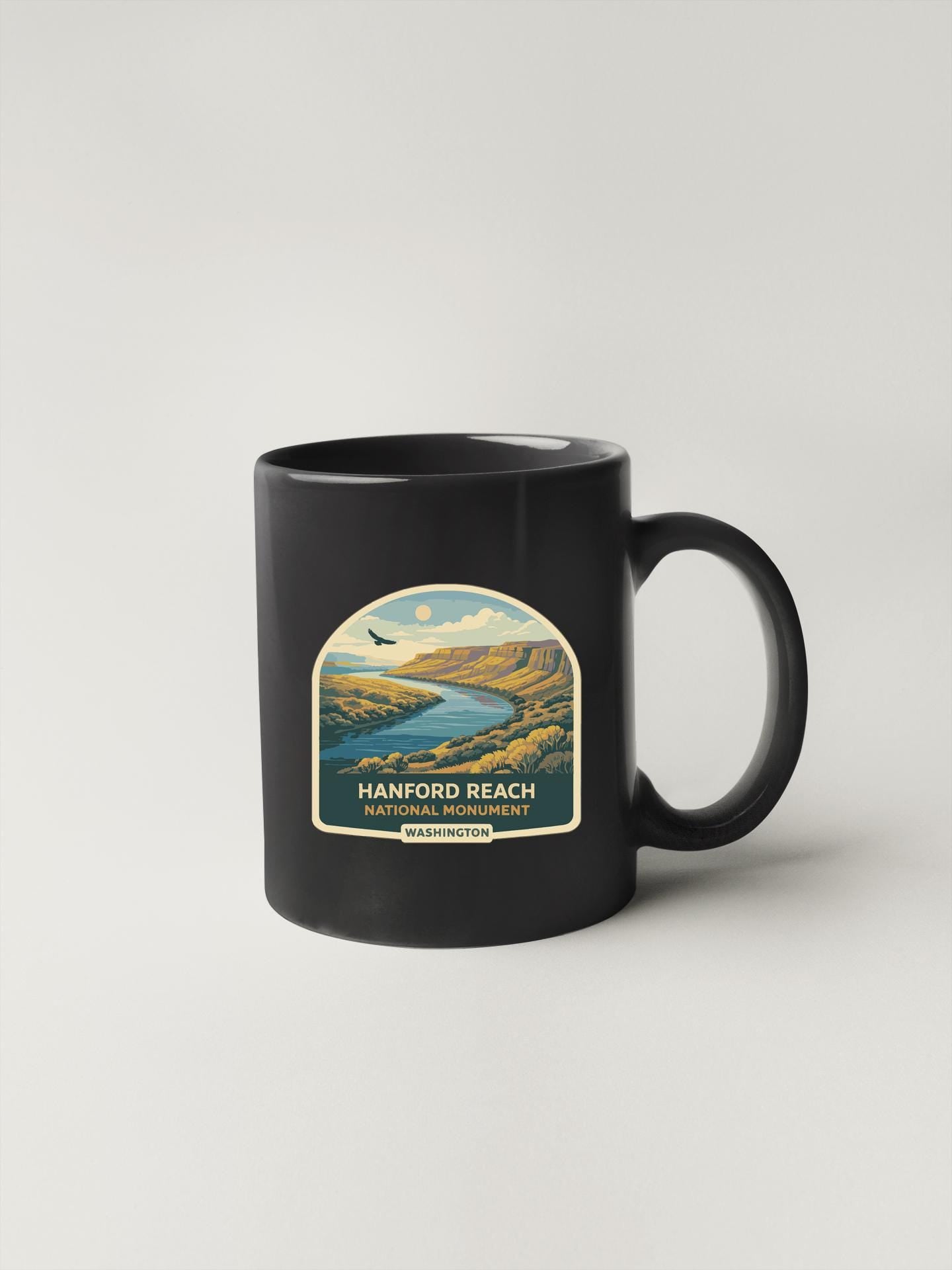 A black coffee mug with a label that says "HANFORD REACH NATIONAL MONUMENT WASHINGTON".