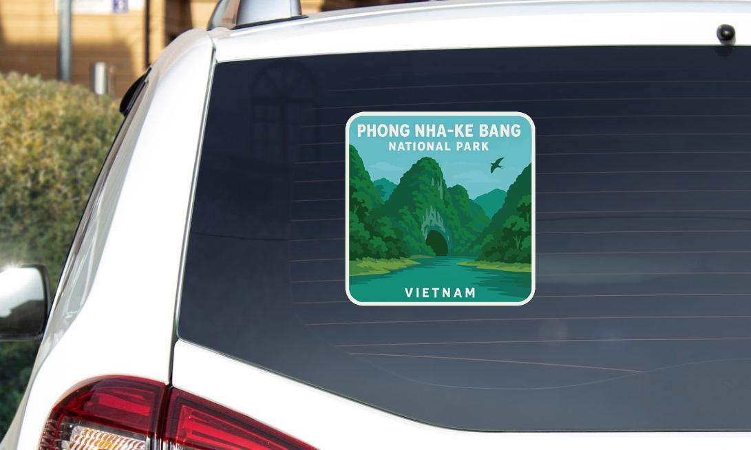 a sticker on the rear window of a car, depicting a scenic landscape with mountains and a river.