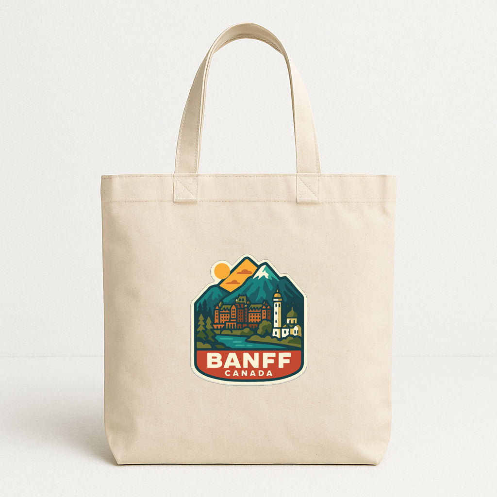 A beige tote bag with a printed design depicting a scenic mountain landscape and the text "BANFF CANADA" printed on it.