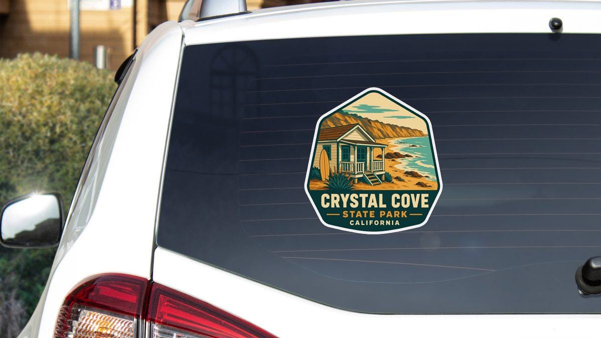 A sticker on the rear window of a white vehicle, depicting a scenic coastal landscape with a house and mountains in the background.