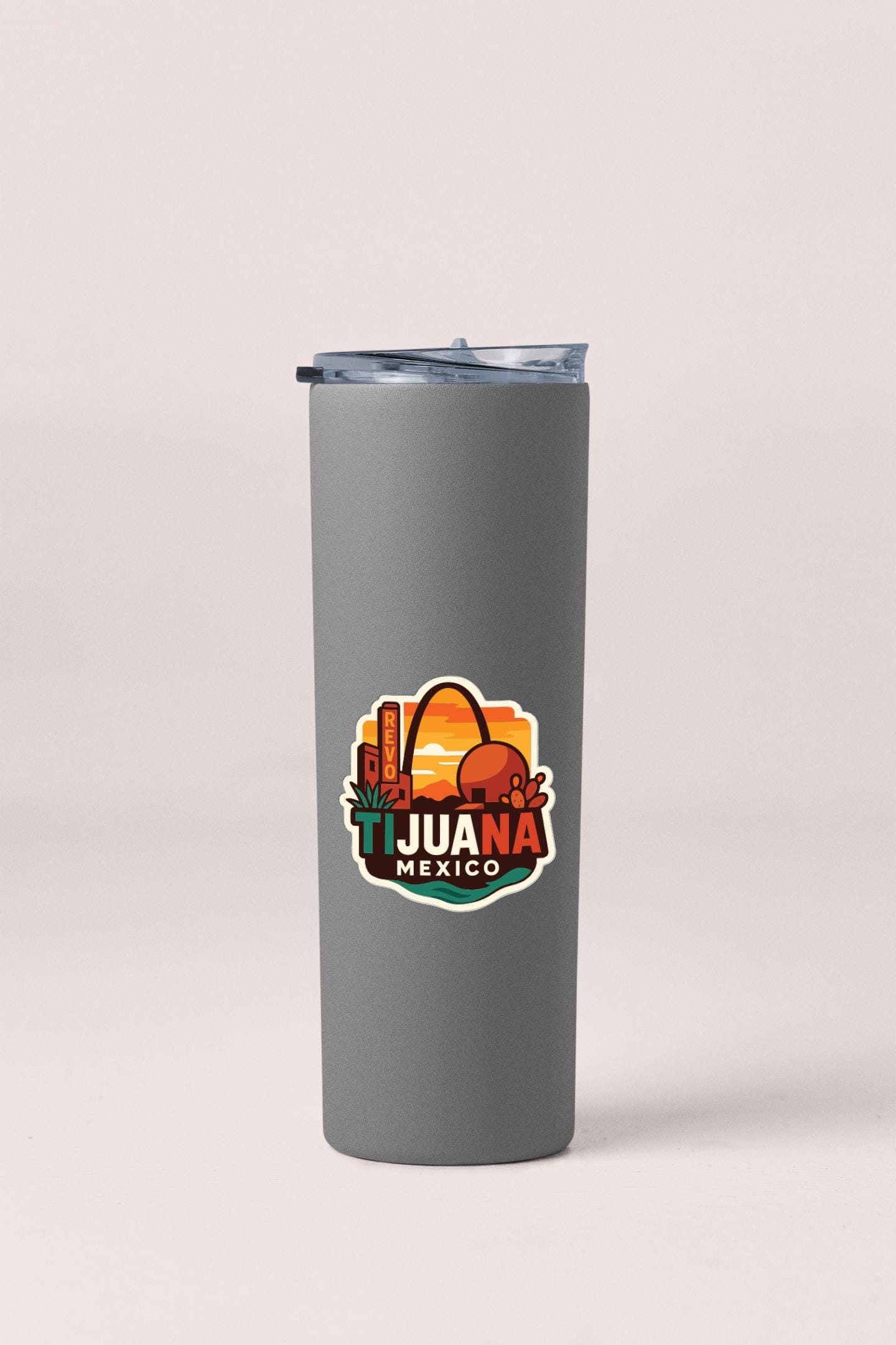 A gray insulated tumbler with a colorful sticker on it, featuring the text "TIJUANA MEXICO" and an illustration of a city skyline.