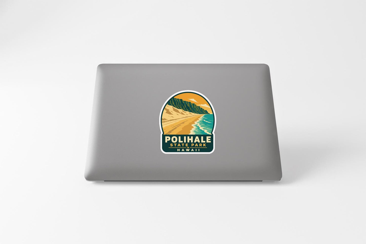 A sticker on the back of a laptop, depicting a scenic landscape with mountains, a beach, and a sunset.