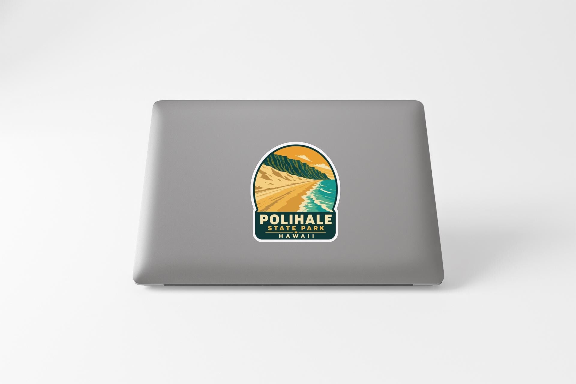 A sticker on the back of a laptop, depicting a scenic landscape with mountains, a beach, and a sunset.