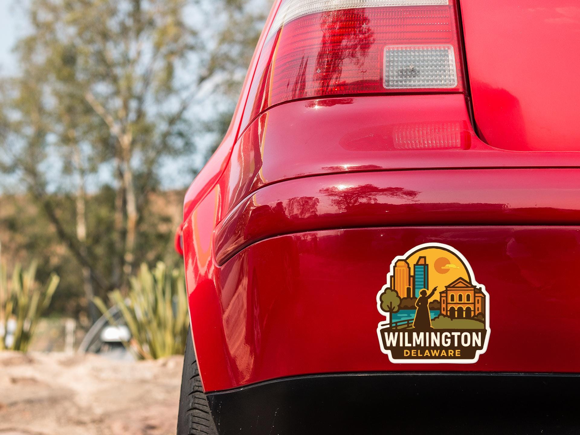 the rear end of a red car with a sticker on the trunk that says "Wilmington Delaware".