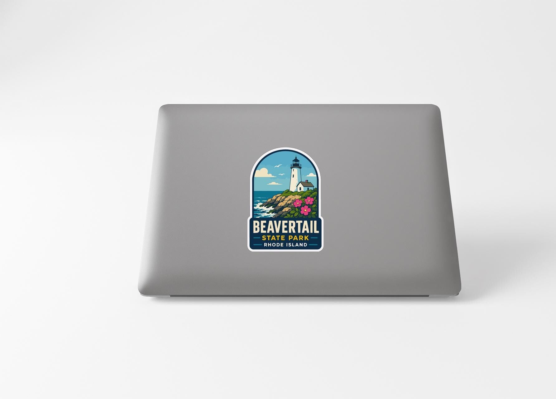 A sticker on the back of a laptop, depicting a lighthouse and the text "BEAVERTail Shore Island".