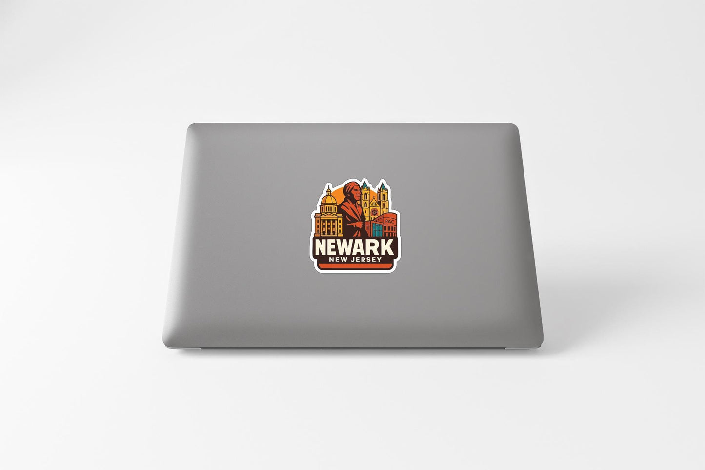 a sticker with a cityscape and the text "NEWARK" on a laptop.