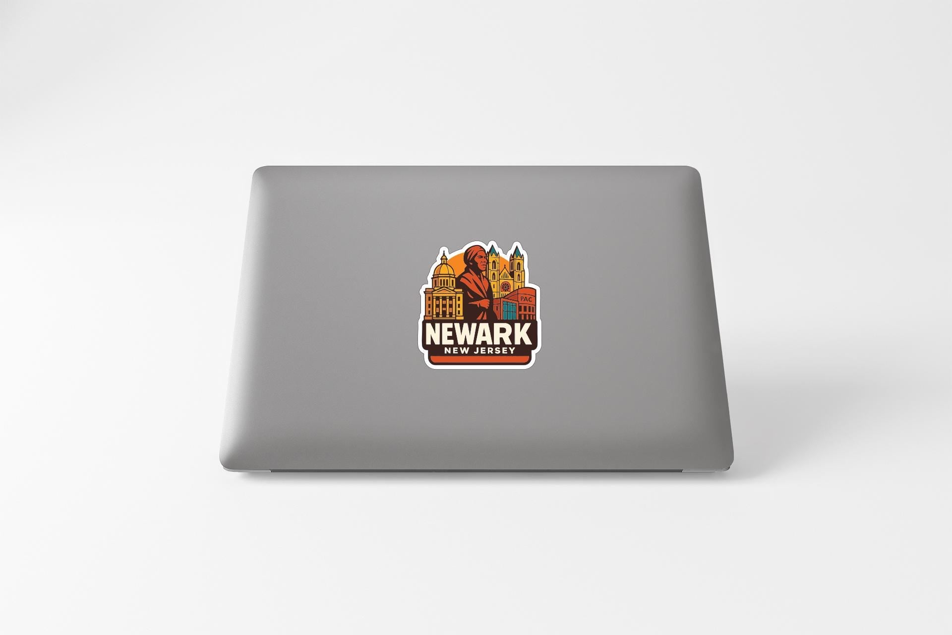a sticker with a cityscape and the text "NEWARK" on a laptop.