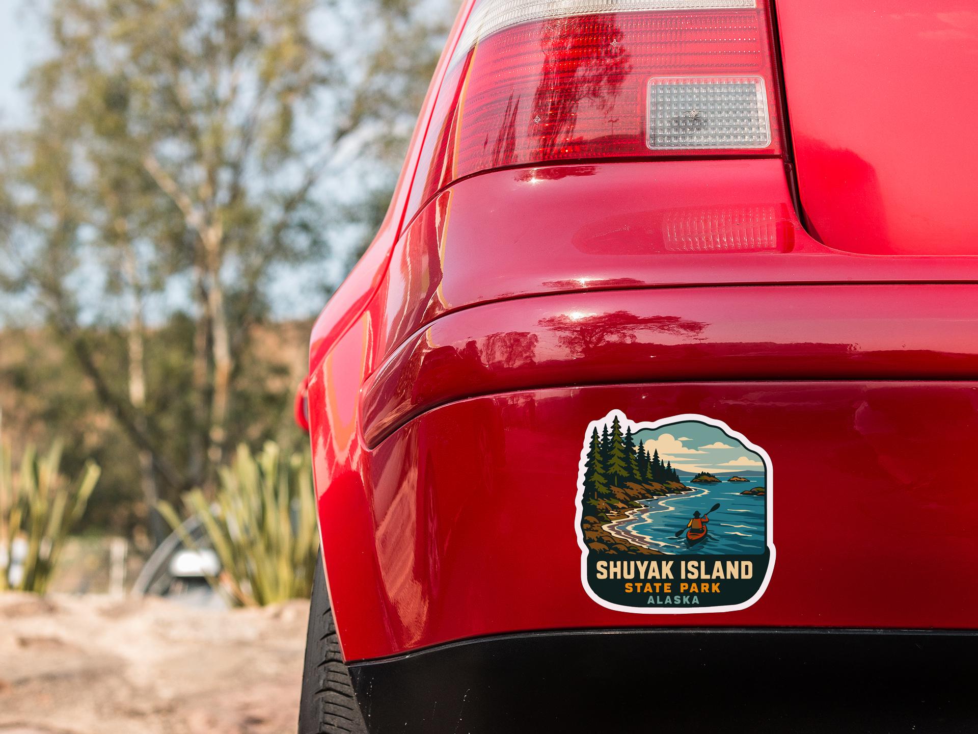 the rear end of a red car with a sticker on the back window that says "SHUYAK ISLAND STATE PARK ALASKA".