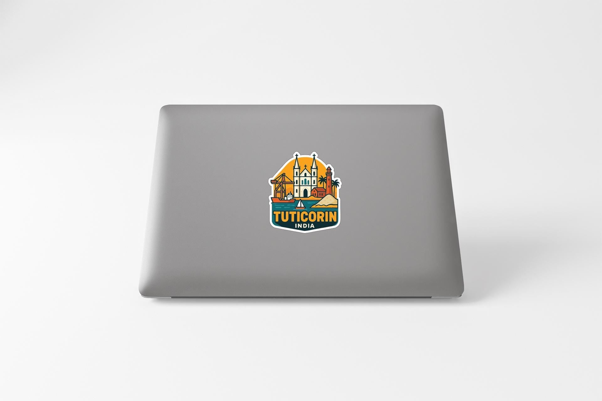 A sticker on the back of a laptop displaying a colorful illustration of a building with a palm tree and the text "TUTICORIN".