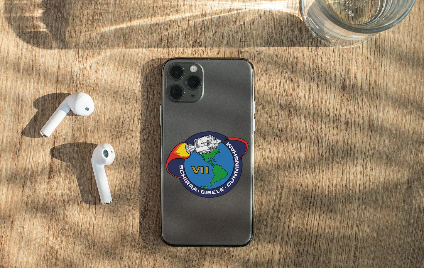 a cell phone with a sticker on it next to ear buds
