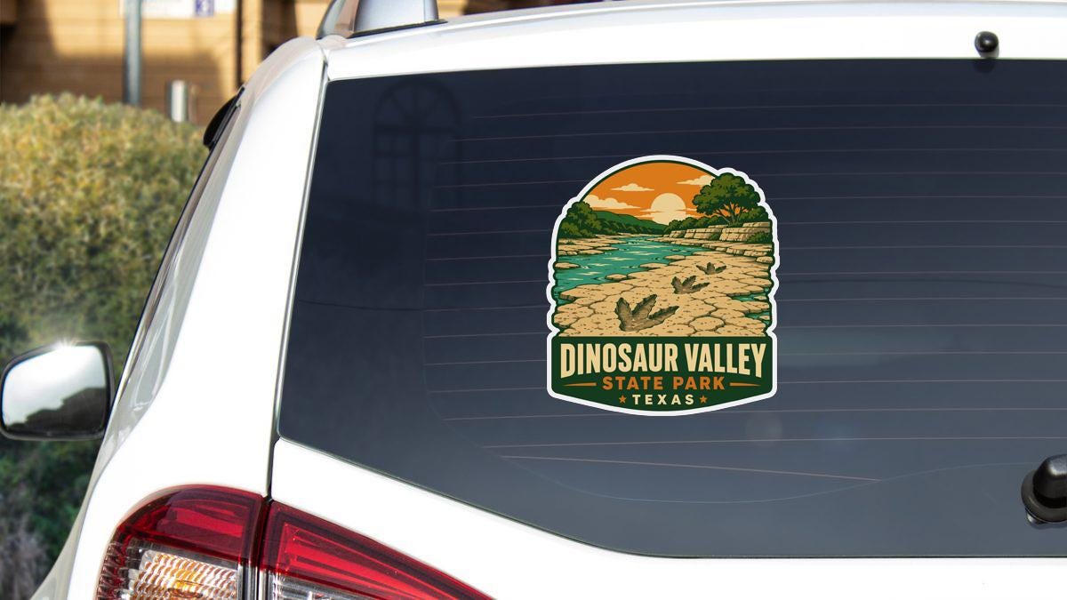 A sticker on the rear window of a white vehicle, depicting a scenic landscape with a river and mountains, advertising Dinosaur Valley State Park in Texas.