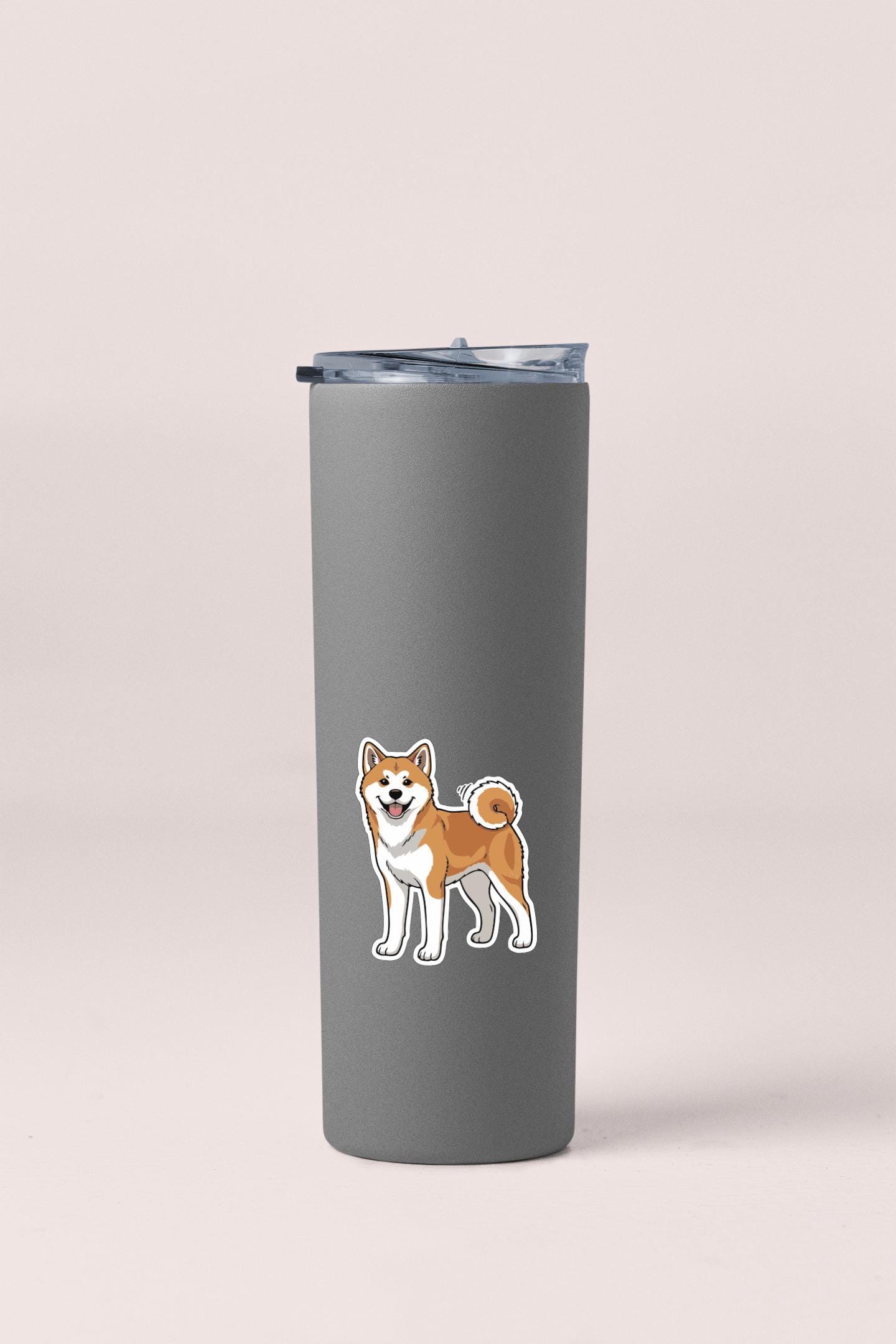 A gray insulated tumbler with a sticker of a Shiba Inu dog on it.