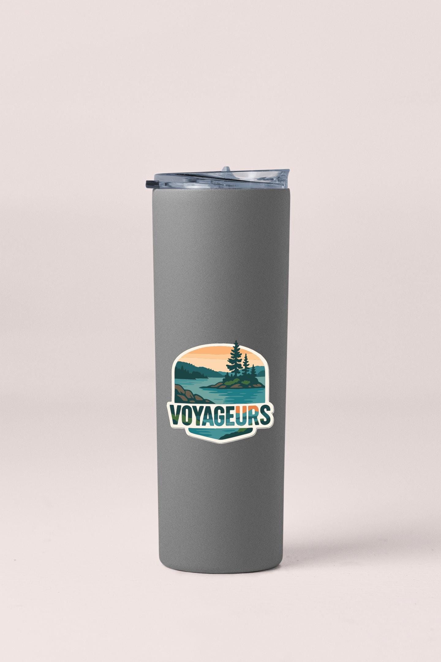 A gray insulated tumbler with a lid and a sticker featuring a scenic landscape.