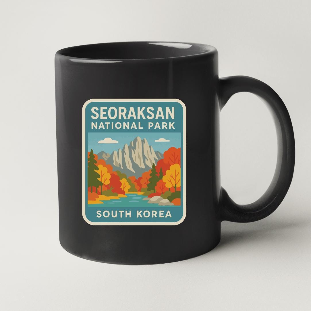 A black coffee mug with a sticker depicting a scenic landscape of mountains, trees, and a river, along with the text "SEORAKSAN NATIONAL PARK SOUTH KOREA".