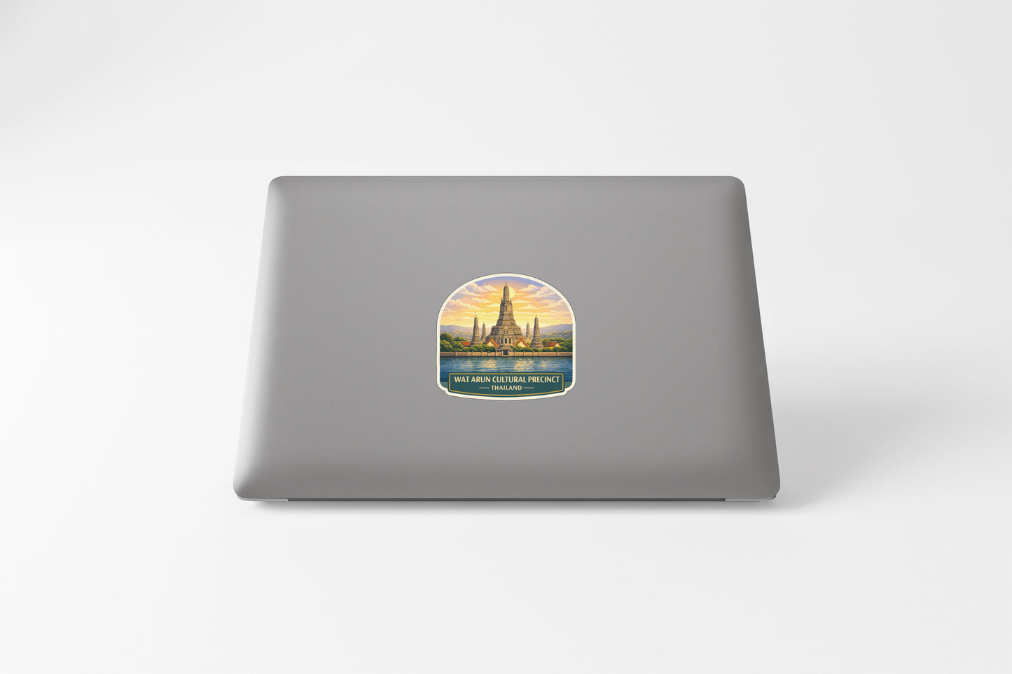 A sticker depicting a temple or monument with a sunset in the background, placed on the back of a laptop computer.
