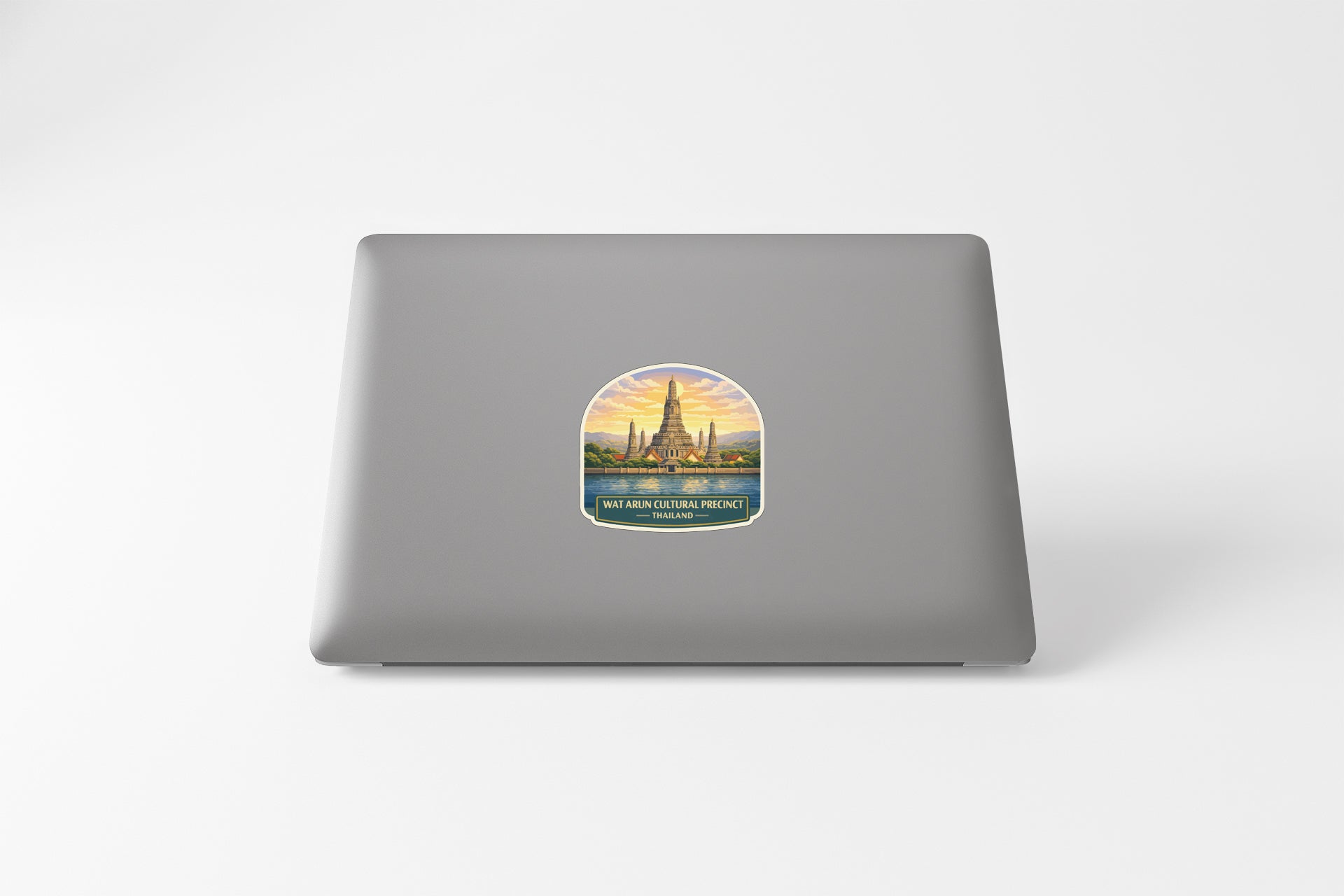 A sticker depicting a temple or monument with a sunset in the background, placed on the back of a laptop computer.