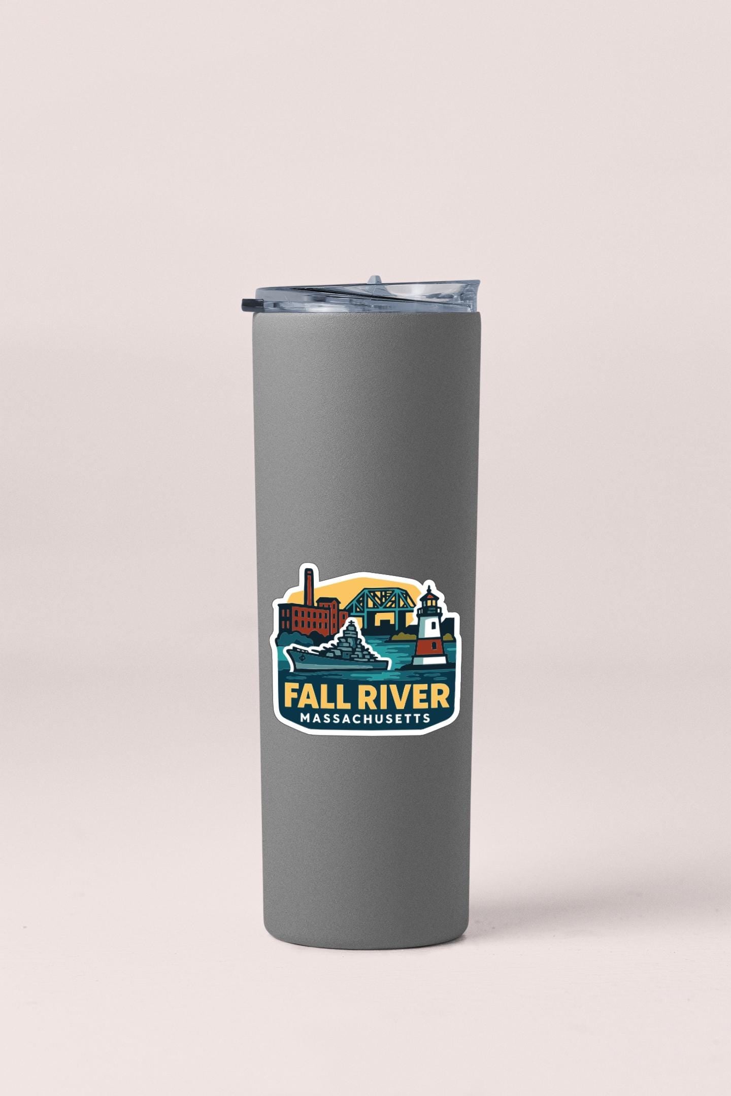 A gray insulated tumbler with a lid and a sticker featuring an illustration of Fall River, Massachusetts.
