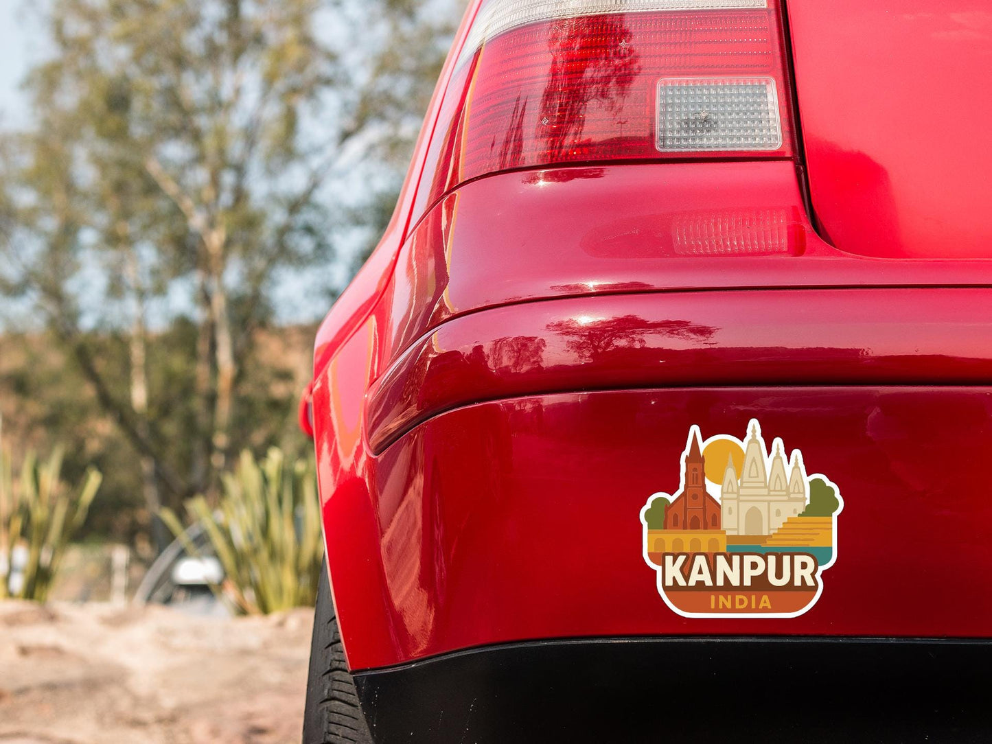 the rear end of a red car with a sticker on the trunk that says "Kanpur India".