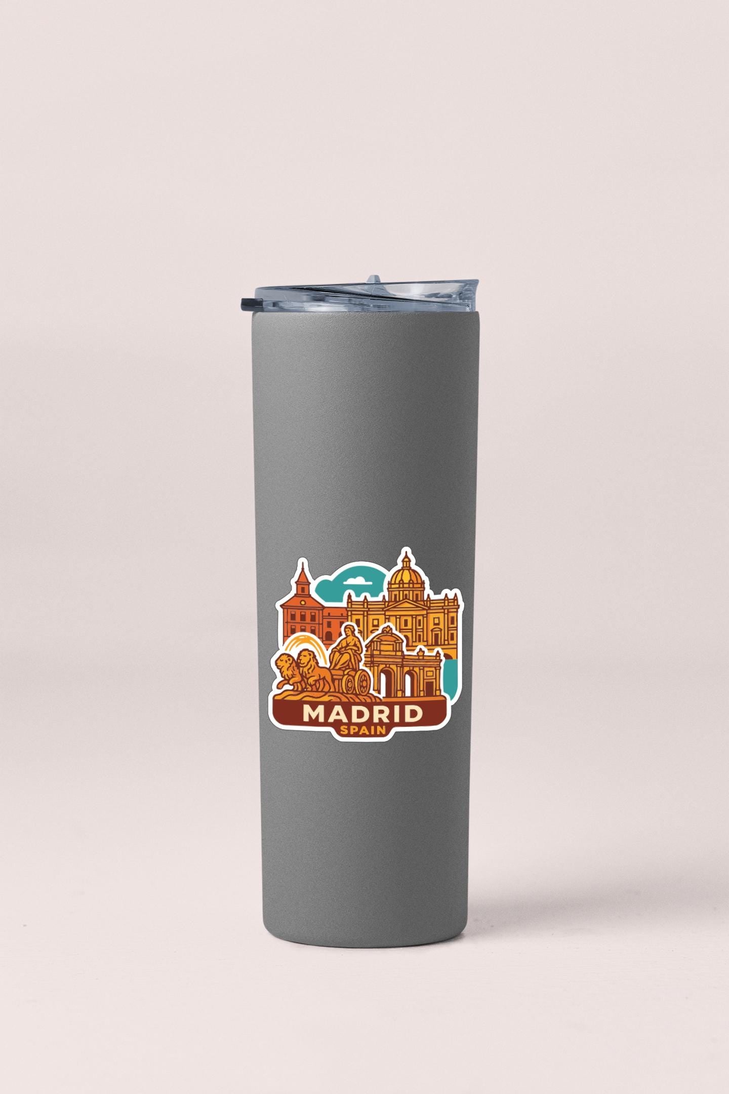 A gray insulated tumbler with a sticker depicting the city of Madrid, Spain.