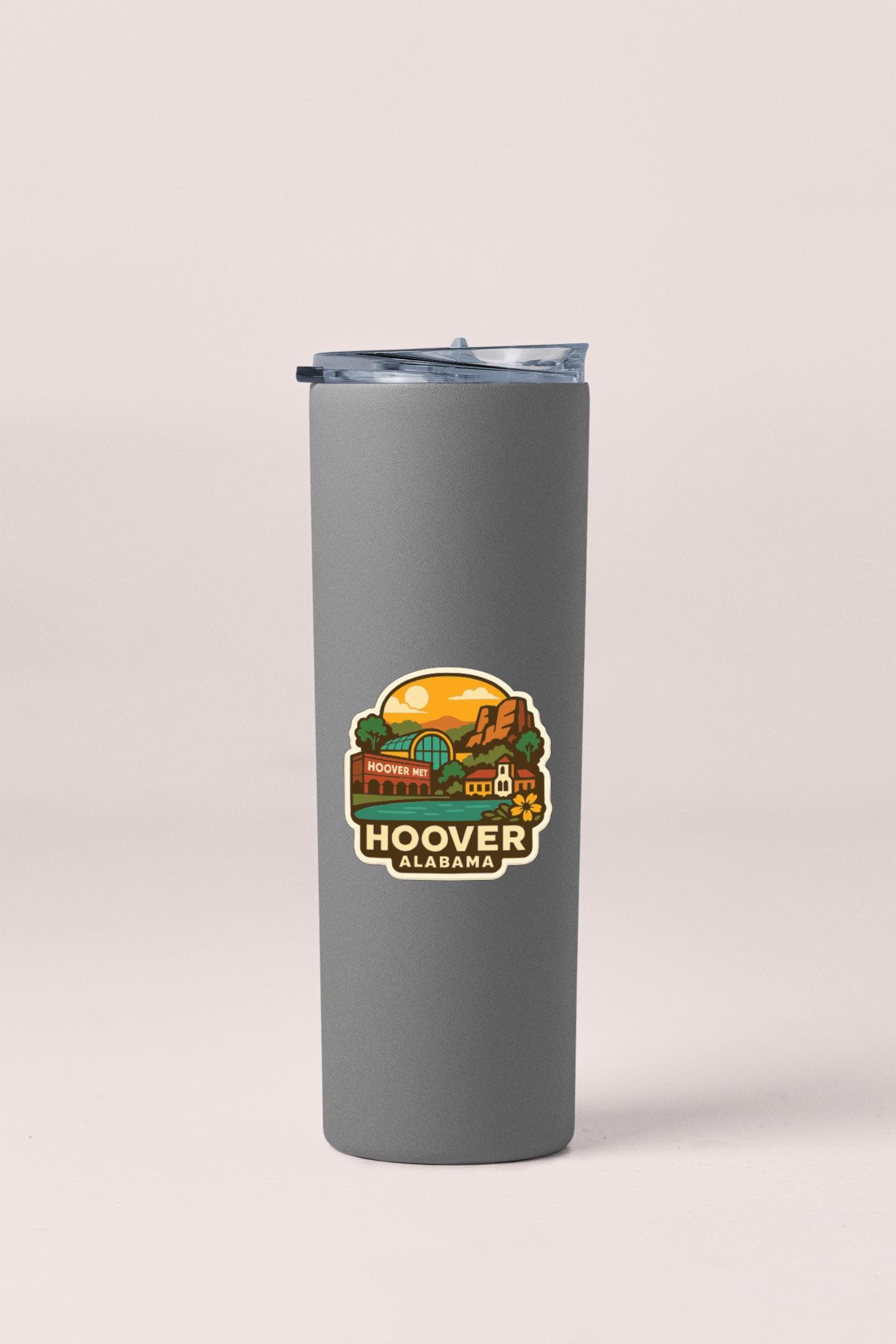 A gray insulated tumbler with a sticker depicting a scenic view of Hoover, Alabama.