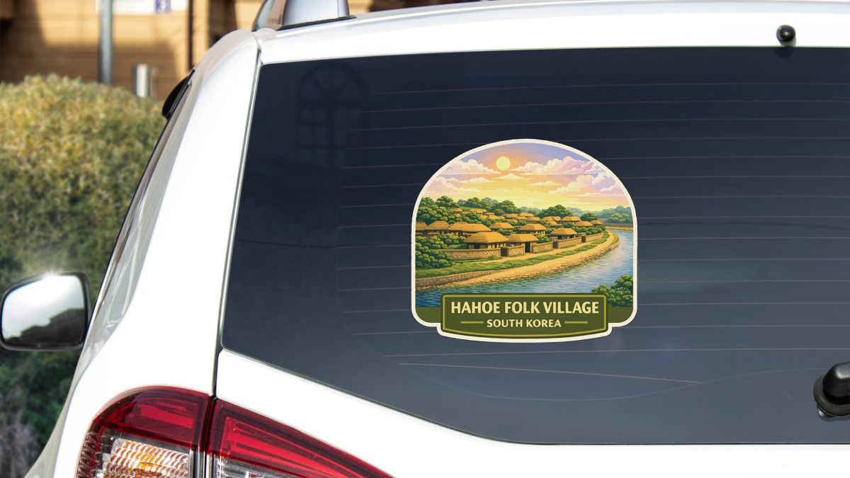 A sticker on the rear window of a car depicting a scenic rural landscape with a village and a river.