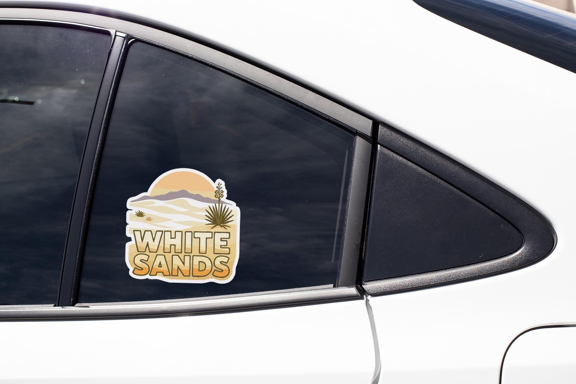 A sticker on the side of a car window that says "WHITE SAND".