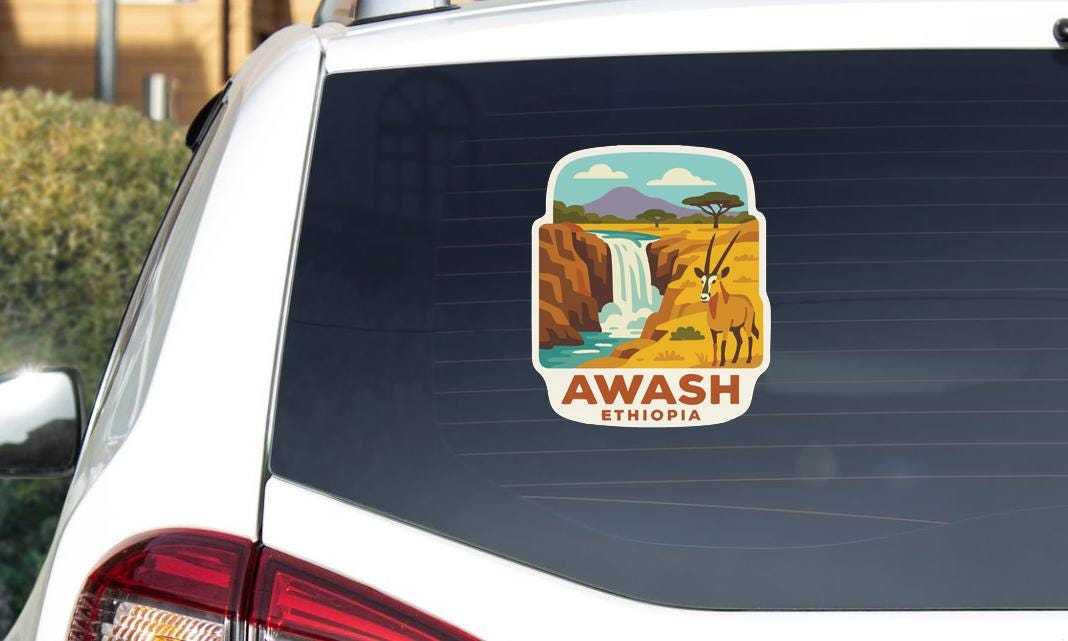 A sticker on the rear window of a car, depicting a scenic landscape with a waterfall and a gazelle.