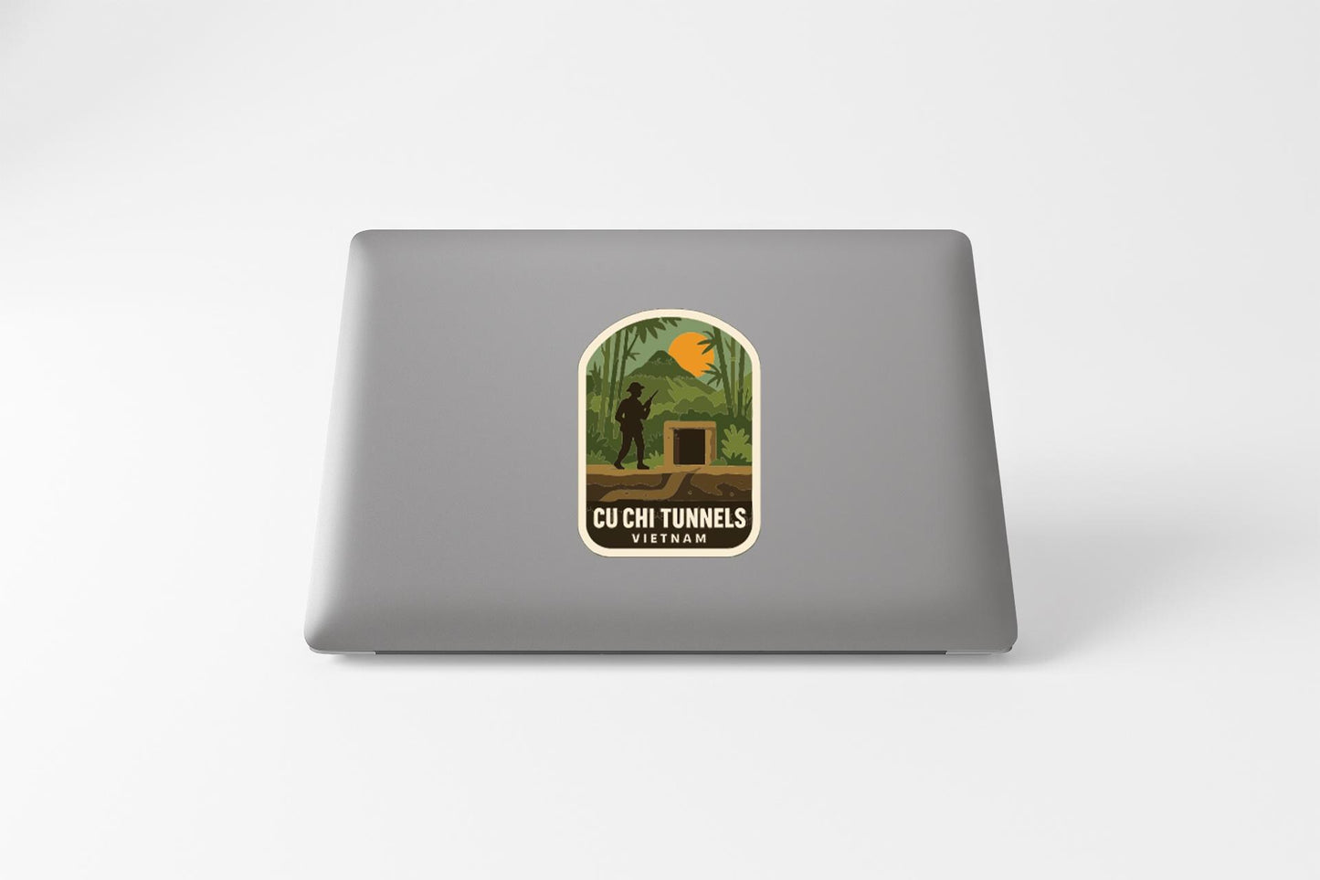 a sticker on a laptop that depicts a person walking through a tunnel surrounded by tropical foliage.