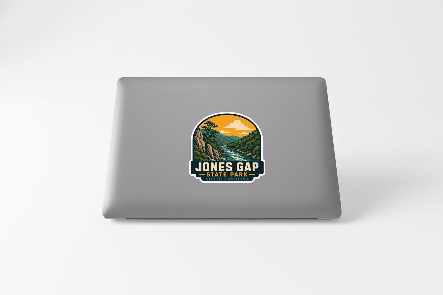 A sticker on the back of a laptop that features a scenic landscape with mountains, a river, and a sunset.