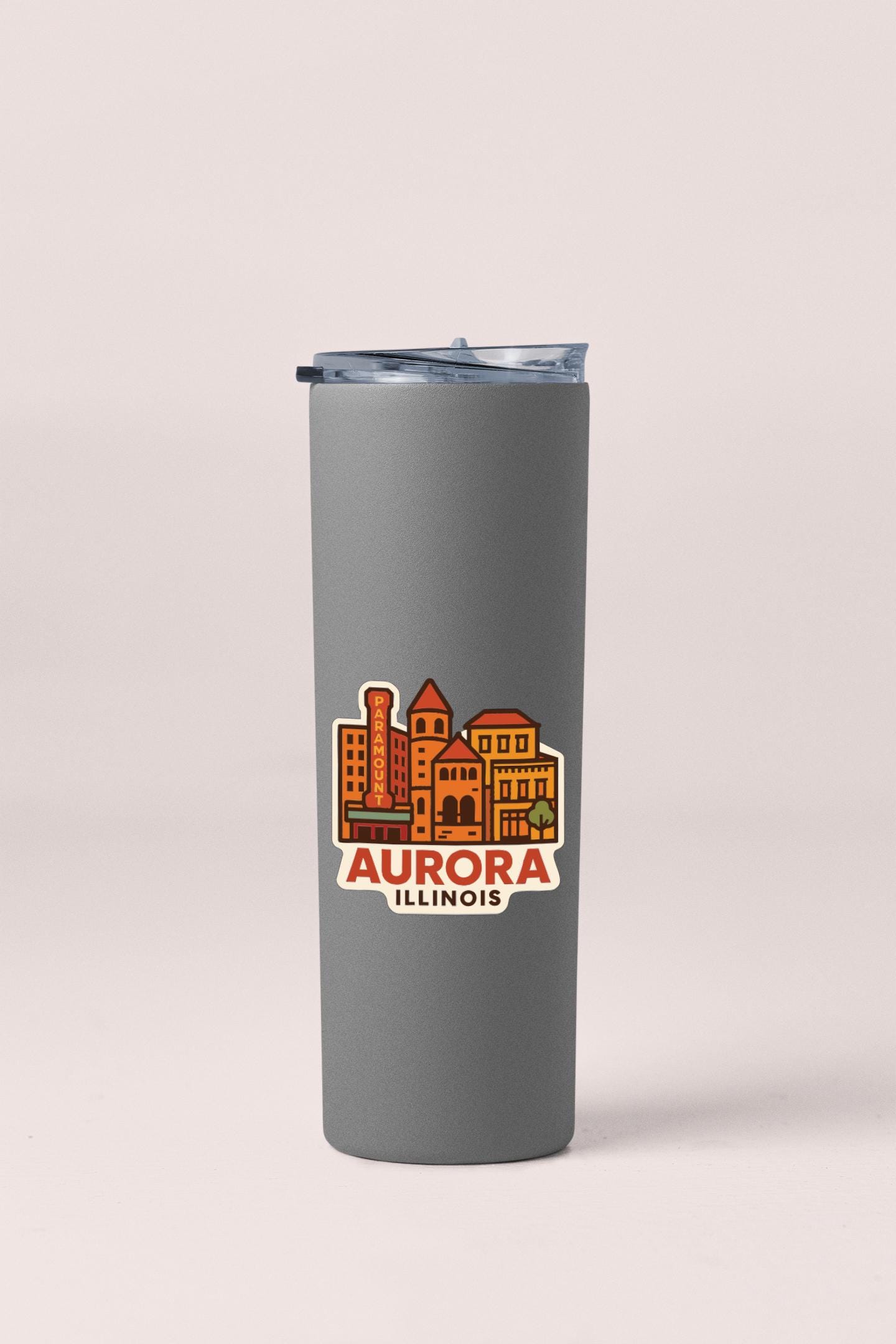 A gray insulated tumbler with a printed design of a city skyline and the text "AURORA ILLINOIS" on it.