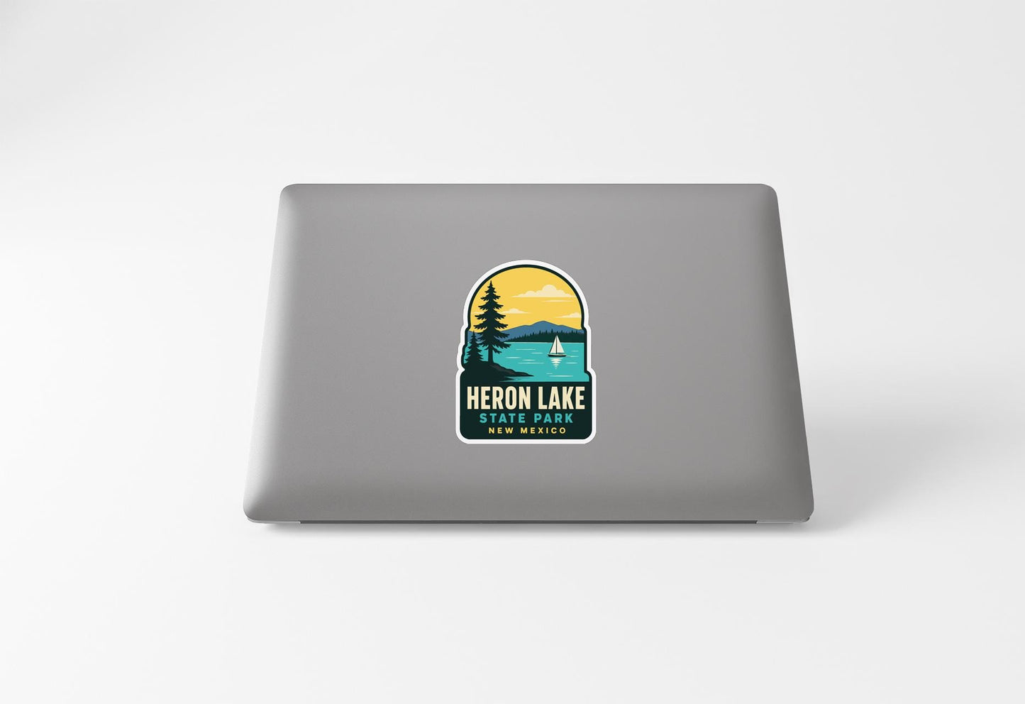 a sticker on a laptop that displays a scenic landscape with a lake, mountains, and a sailboat.