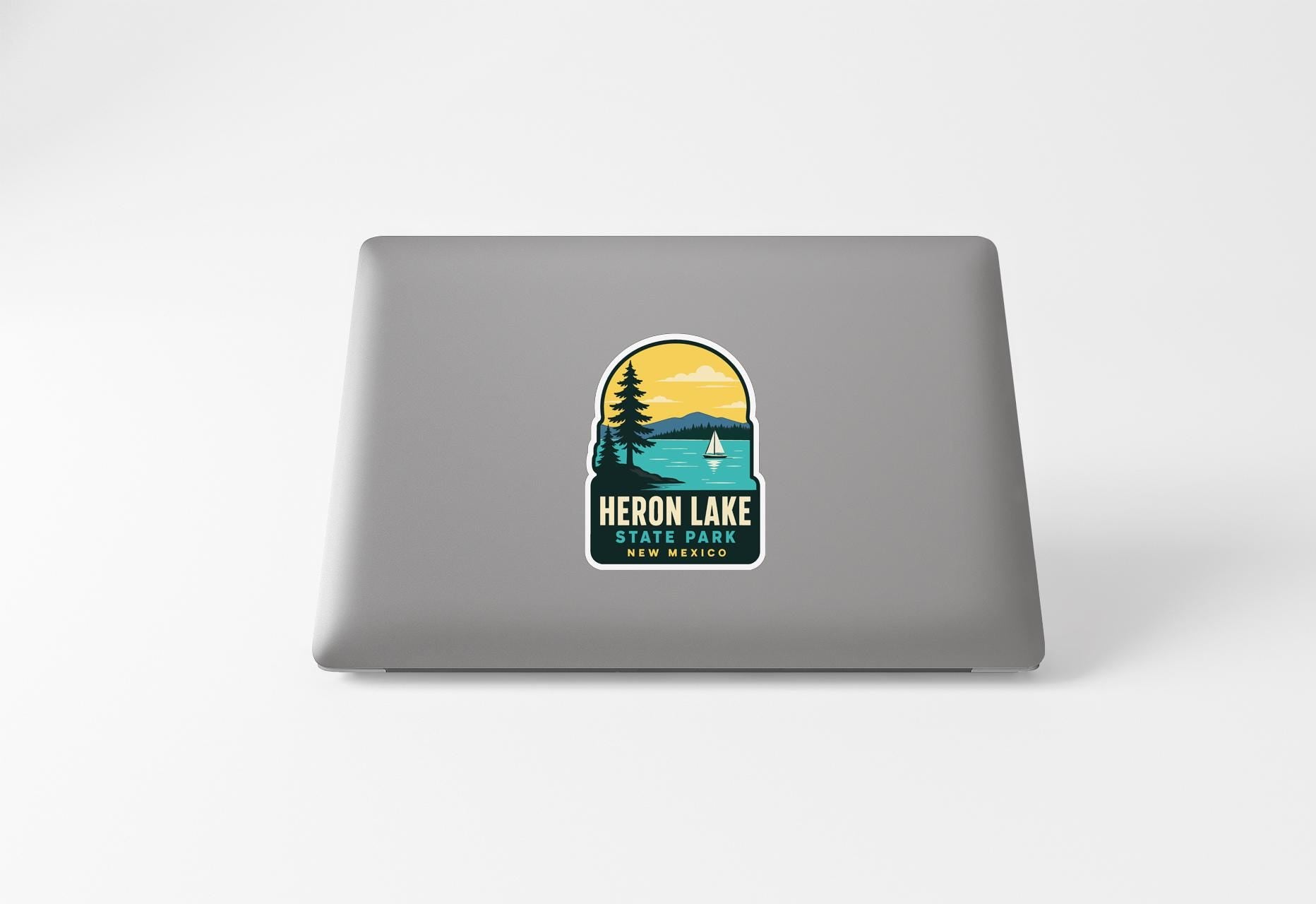 a sticker on a laptop that displays a scenic landscape with a lake, mountains, and a sailboat.