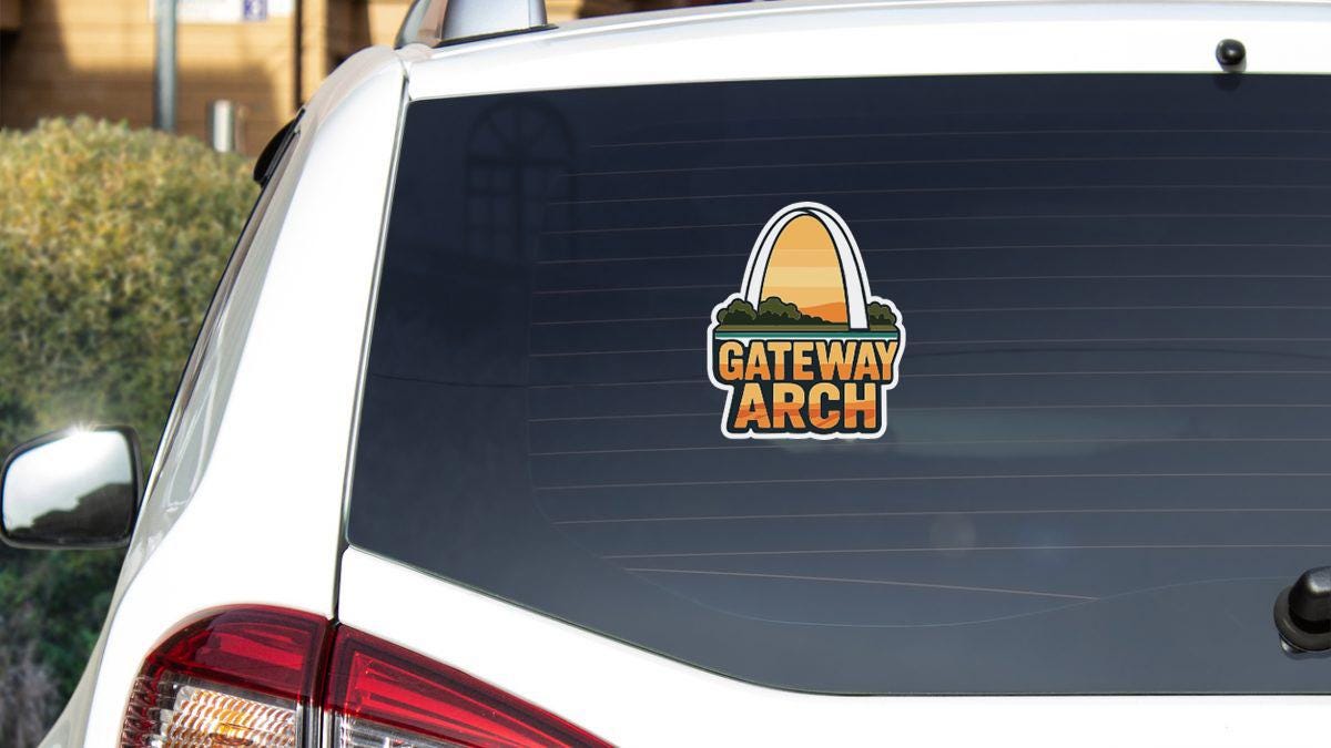 the rear window of a white car with a sticker on it.